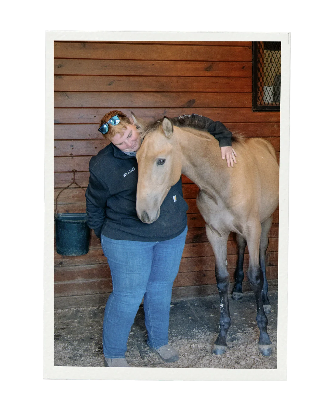 Killian Thorne embracing a young horse in the barn